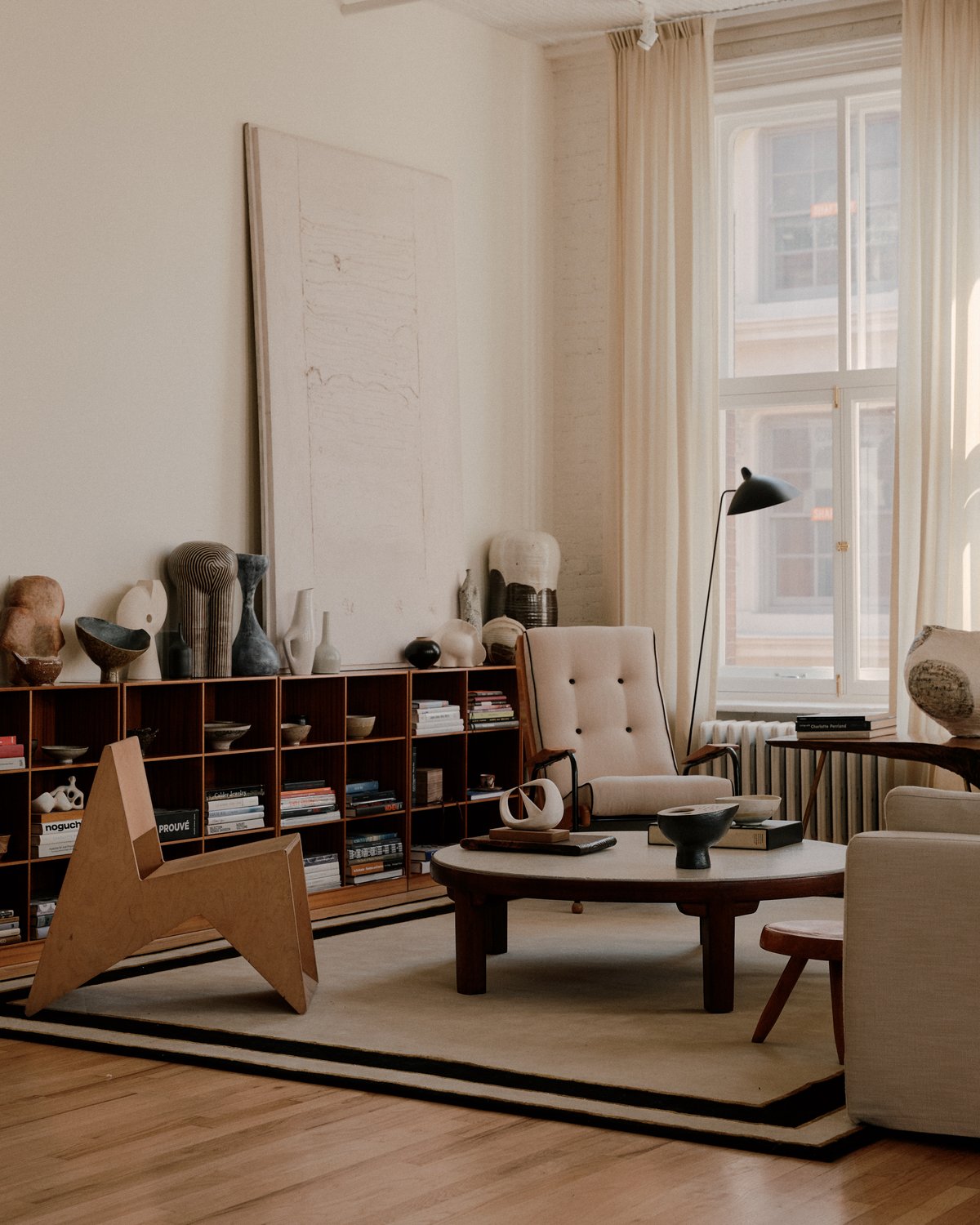 Tapis en laine moelleux Gild 01, photographié dans un salon lumineux avec des détails d’intérieur en bois et de hautes fenêtres.