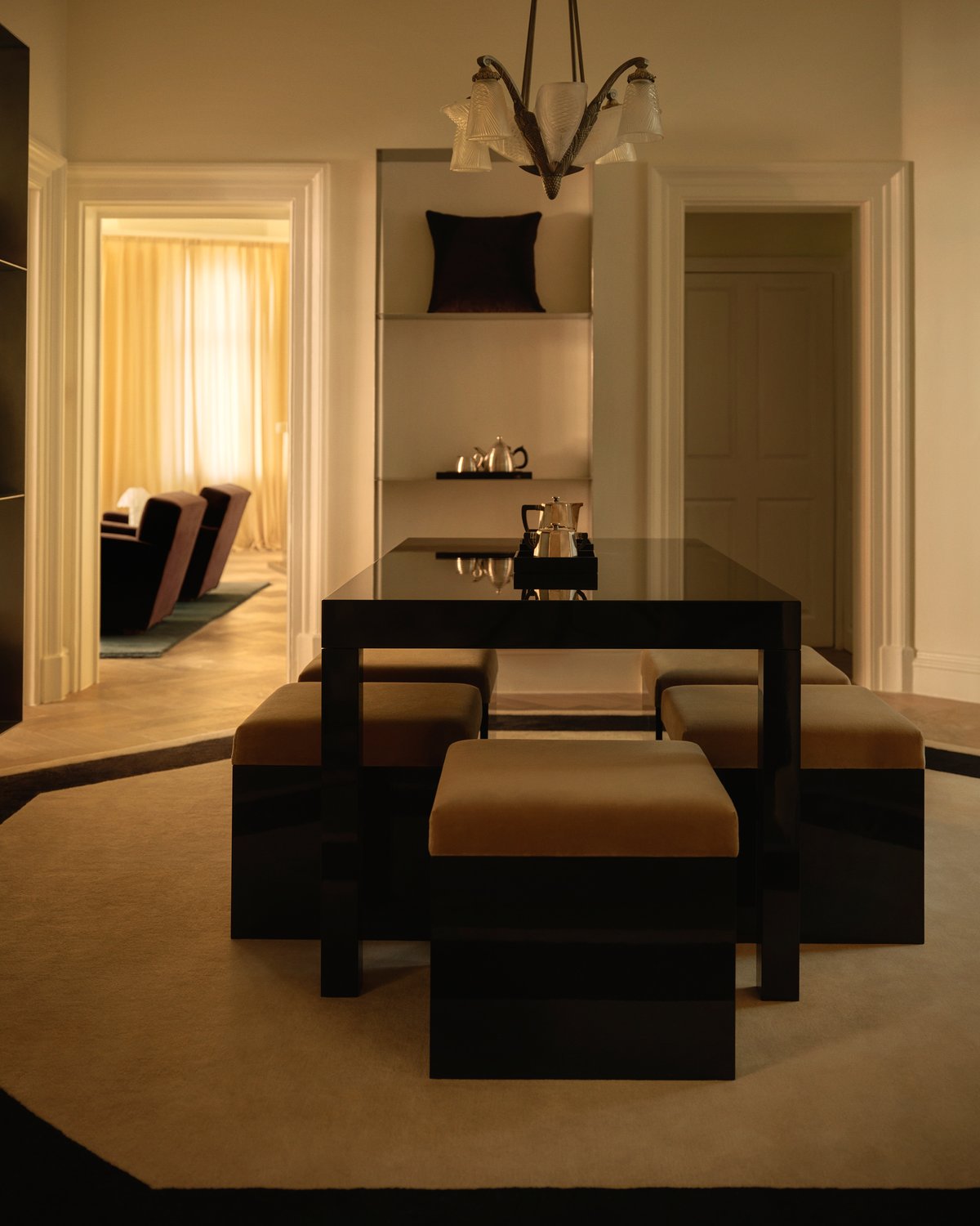 The Grace 05 rug in Octagon is shown in the Nordic Knots store on Mount Street in London, styled in a lounge room with glossy black furniture and soft golden lighting, creating an elegant and architectural atmosphere.