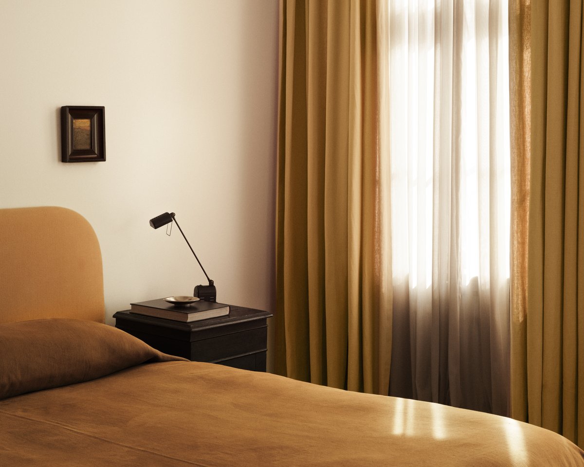 Nordic Knots The Sheer curtains pictured with the sunlight coming through a window onto a rust orange colored bed.