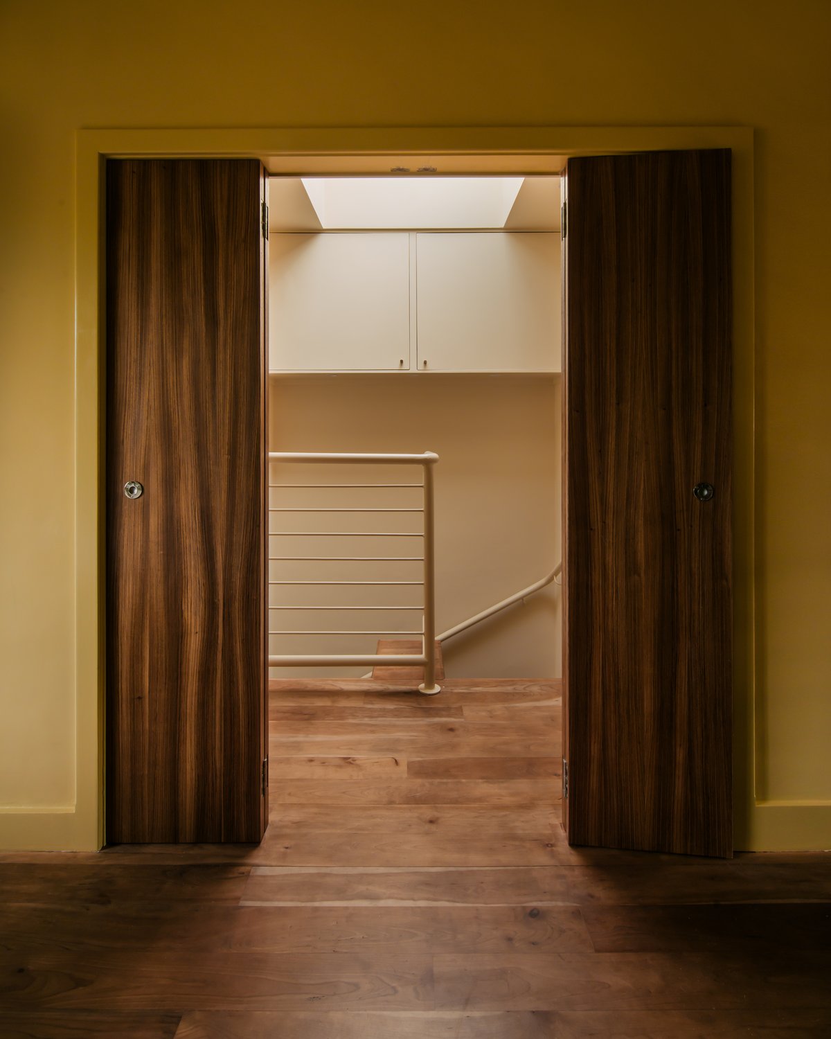 Ein Flur mit gelben Wänden im Zuhause von Hollie Bowden, fotografiert in London, Großbritannien.