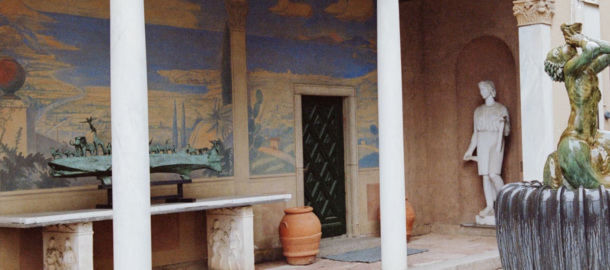 Courtyard with mural, statues, and classical columns.
