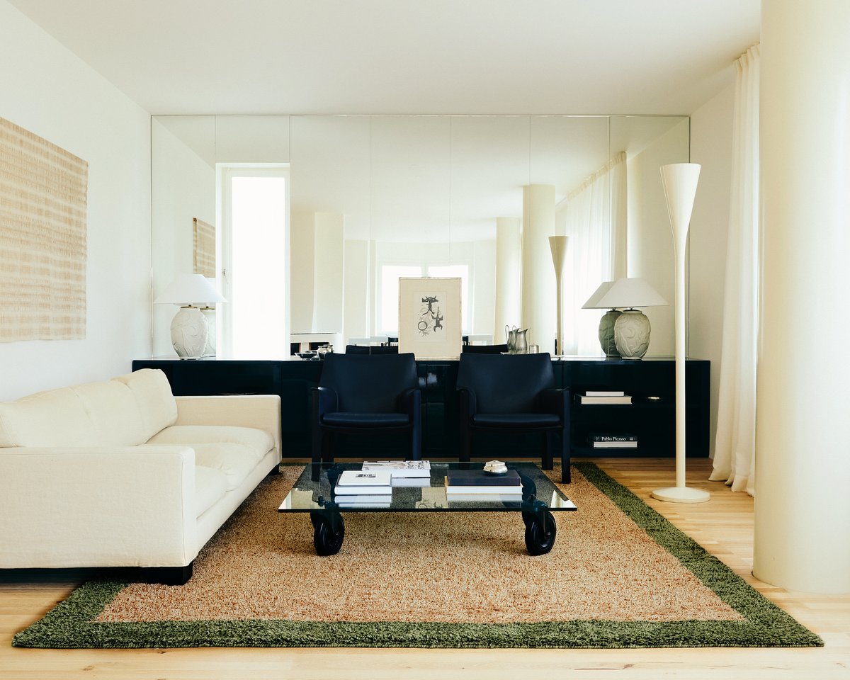 Shaggy wool rug Ryya in Beige pictured in a brightly lit living room with black interior design details and a white sofa.