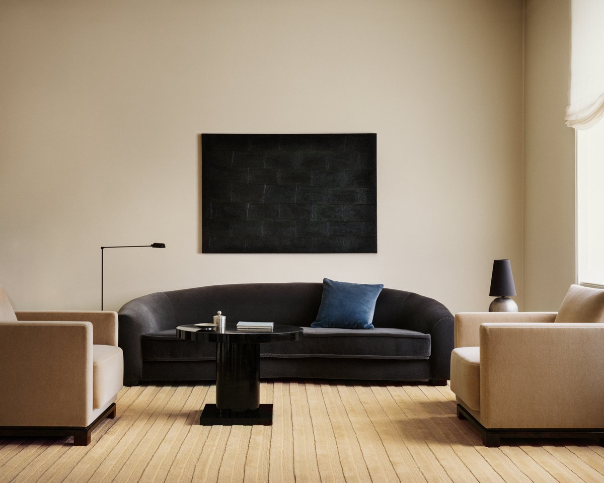 Park 03 rug in Sunrise – a warm golden-toned rug with tonal vertical stripes, grounding a minimalist living room with sculptural seating and a deep-toned sofa.